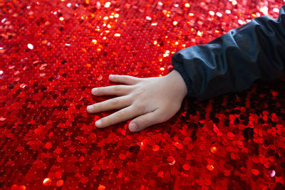 Cropped hands of children on red glitters