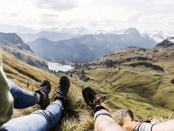 Low section of people on mountains against sky