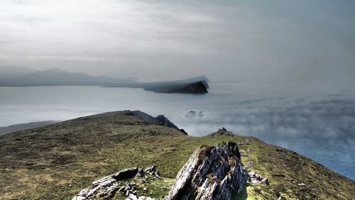 Idyllic shot of sea and mountains against cloudy sky