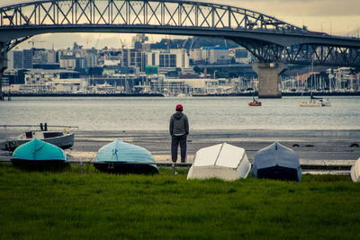 Side view of man on river by city against sky