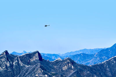 Under the clear blue sky, the plane flew over the great wall and the mountains