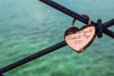 Close-up of padlocks hanging on railing against river