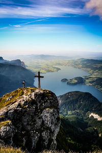 High angle view of hiker standing by cross on cliff