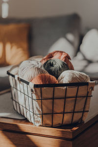 Balls of earth coloured yarn inside a basket on a table inside an apartment.