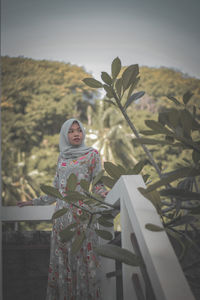 Portrait of smiling woman standing against plants