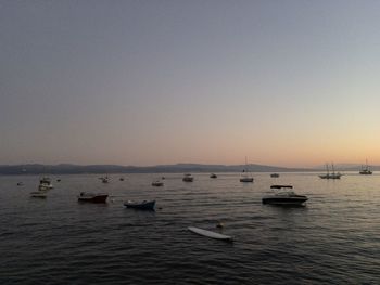 Sailboats in sea against clear sky at dusk