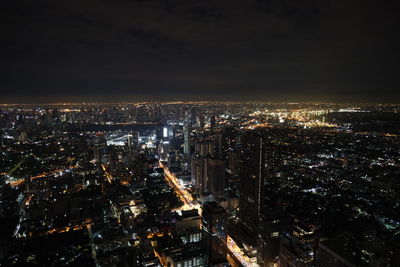 Illuminated cityscape against sky at night