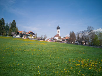 Scenic view of field by buildings against sky