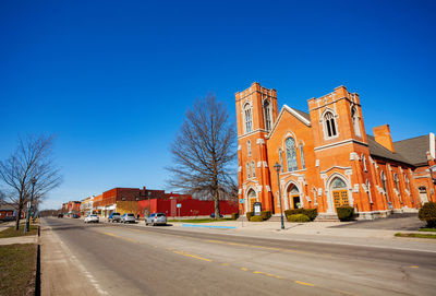 Road by buildings against blue sky