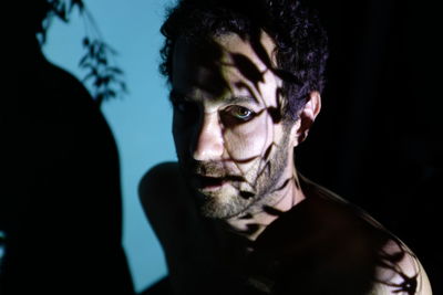 Portrait of shirtless man against wall with shadow