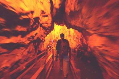 Rear view of people walking in tunnel