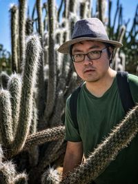 Portrait of young man wearing hat and surrounded by tall cacti
