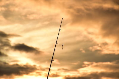 Low angle view of silhouette power lines against dramatic sky