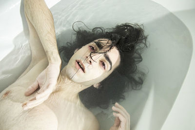 High angle portrait of woman lying down in bathroom