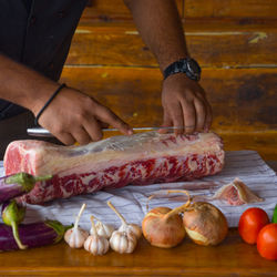 Midsection of chef cutting beef on table