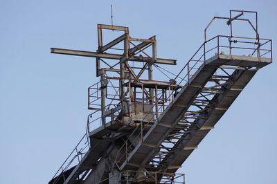 Low angle view of crane against clear blue sky