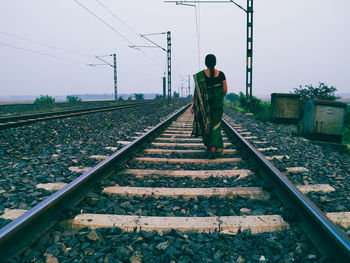 Rear view of man standing on railroad track