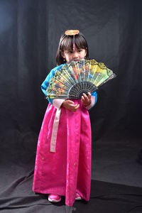 Cute girl in traditional clothing holding hand fan