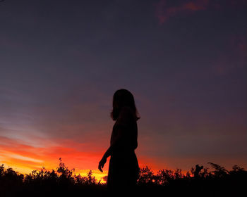 Silhouette woman standing against orange sky