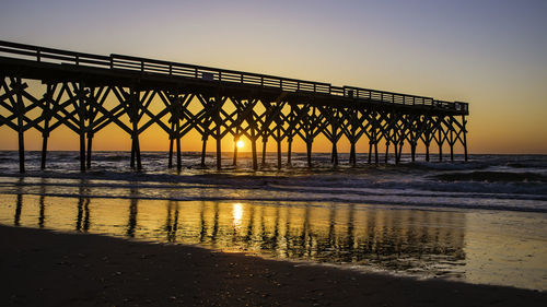 Pier over sea against clear sky during sunset