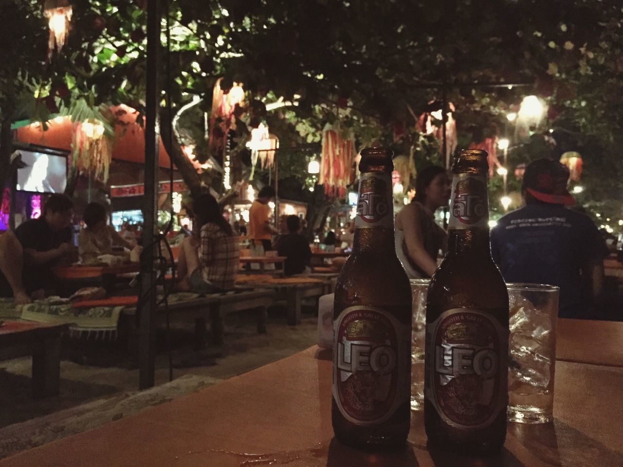 night, street, tree, chair, outdoors, illuminated, transportation, land vehicle, table, incidental people, sunlight, city, no people, car, absence, in a row, sidewalk, metal, still life