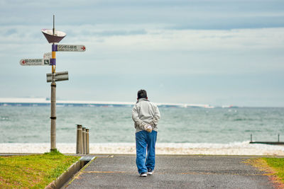 Rear view of man looking at sea against sky