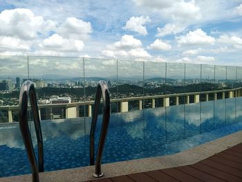 Swimming pool by cityscape against sky
