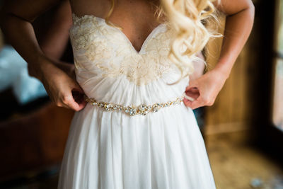 Midsection of woman holding white dress