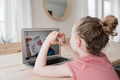 Girl talking to a nurse on a video call with an i love you sign