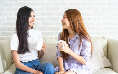 Young woman smiling while sitting against wall