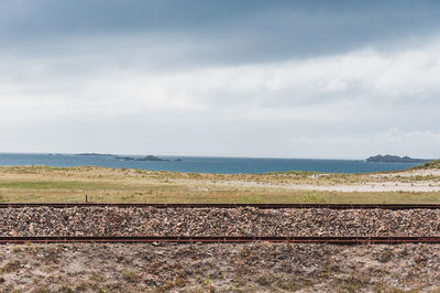 Railroad tracks by sea against sky