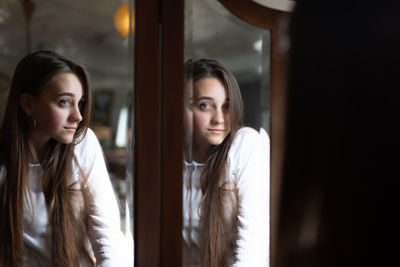 Portrait of beautiful young woman reflecting in mirror