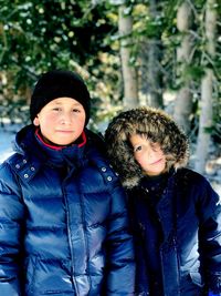 Portrait of siblings in warm clothing standing against trees