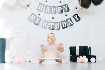 A one year old girl sits on the floor near a sweet cake in honor of her first birthday, tries 