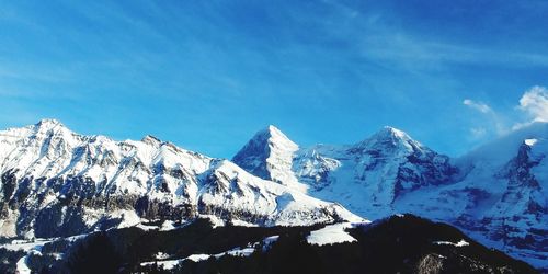 Scenic view of snowcapped mountains against blue sky