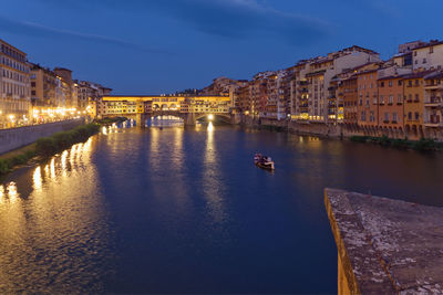 Canal amidst illuminated city buildings against sky at night