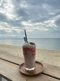 Close-up of drink on table at beach against sky