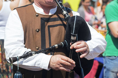 Midsection of man playing bagpipe during event