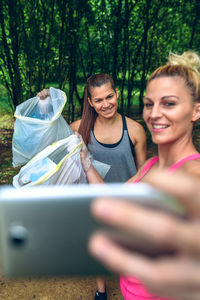 Female volunteers taking selfie while collecting garbage on field