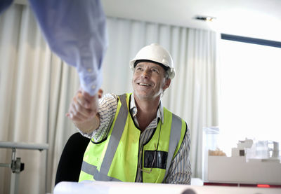 Man in reflective clothing doing handshake with colleague at office