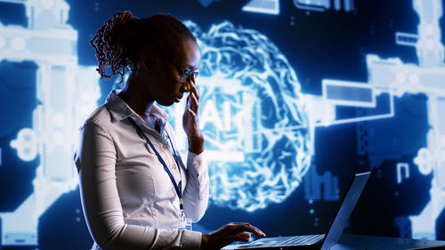 Side view of young woman using mobile phone while standing in office