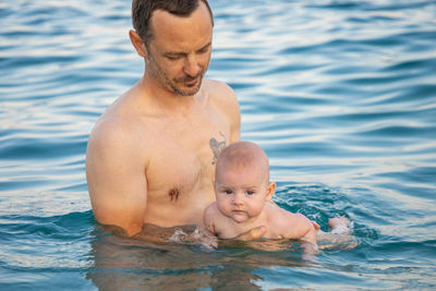 Father and daughter in sea against sky