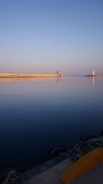 Boats in calm sea against clear sky