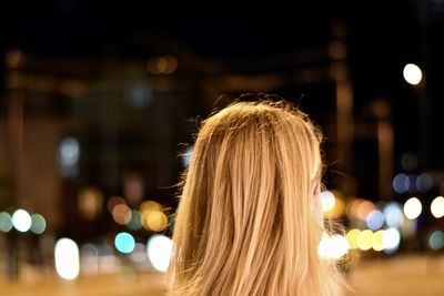 Rear view of woman against illuminated city at night