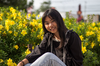 Portrait of young woman against flowering plants