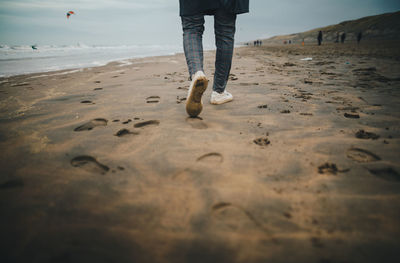 Low section of man walking at beach