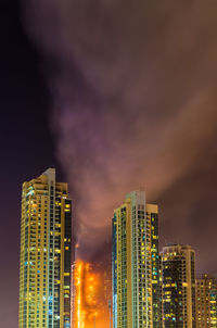 Illuminated modern buildings against sky at night