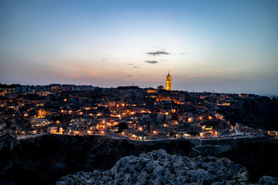 Illuminated buildings in city against sky at dusk