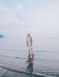 Full length of man standing in sea against sky