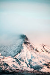 Scenic view of sea by mountain against sky